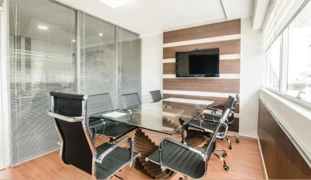 Sala de reuniões com mesa de vidro e cadeiras de escritório